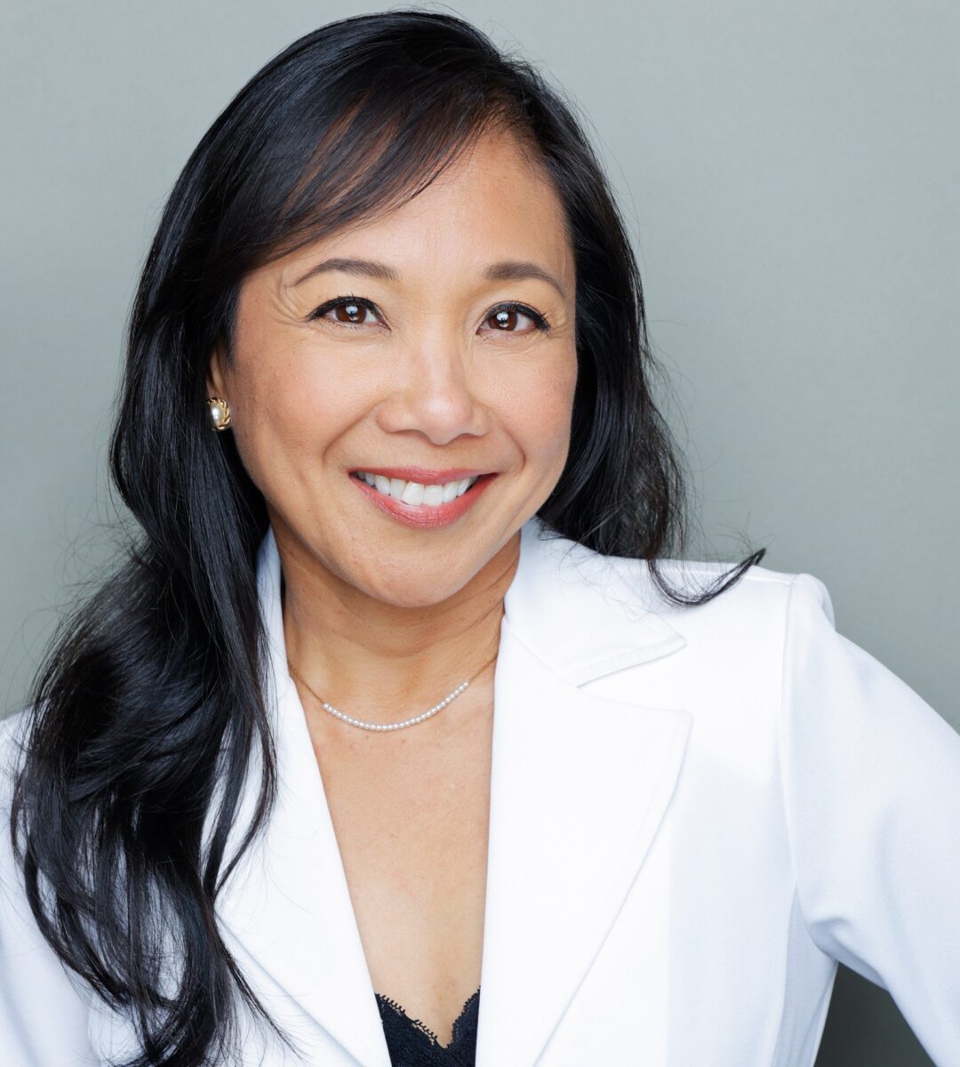 Jennifer Aquino smiling and wearing a lab coat over a black blouse.